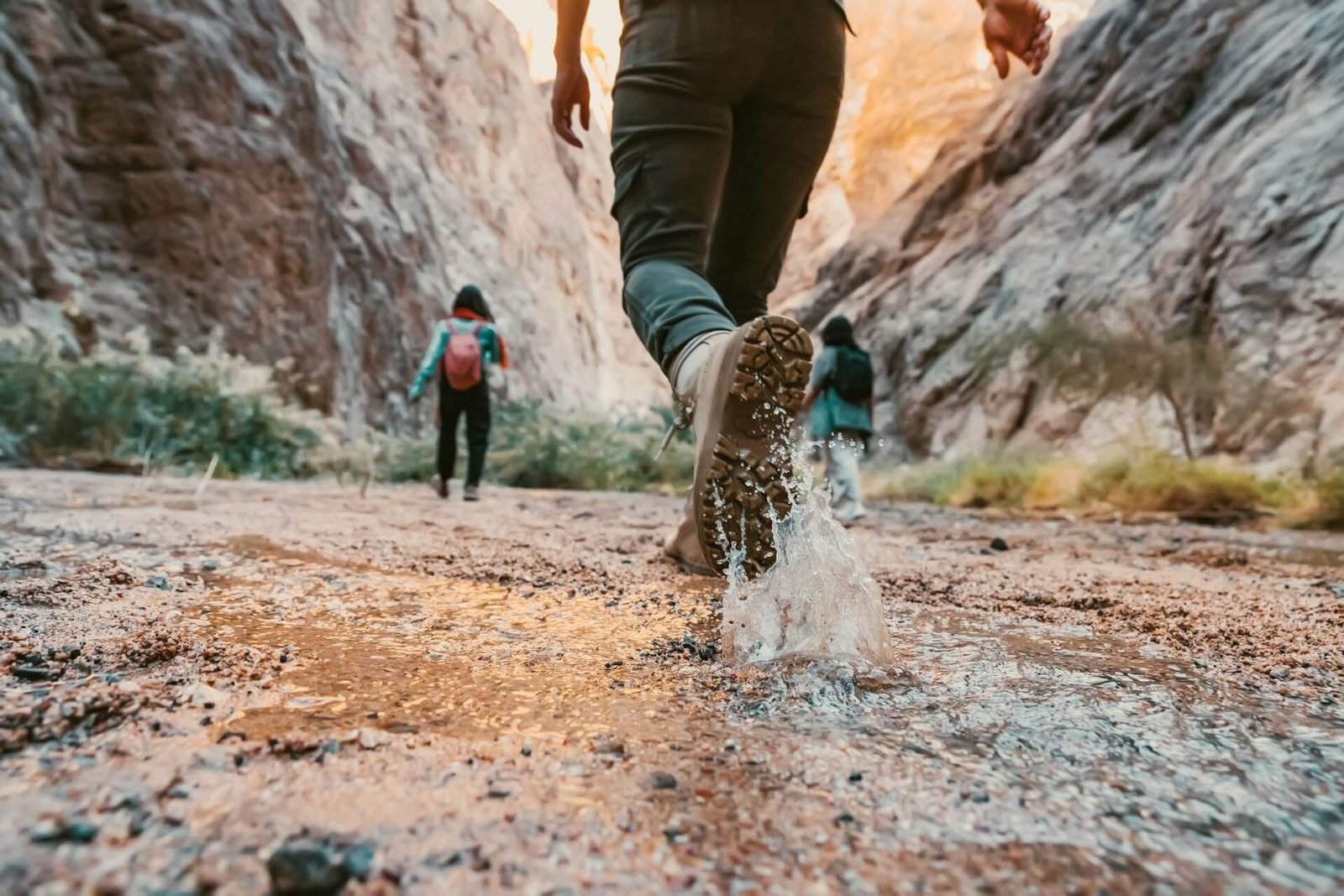 Hiker trekking through water in Sarakina Gorge near Myrtos, wearing hiking boots and splashing water—ideal for adventure tourism in Eastern Crete.
