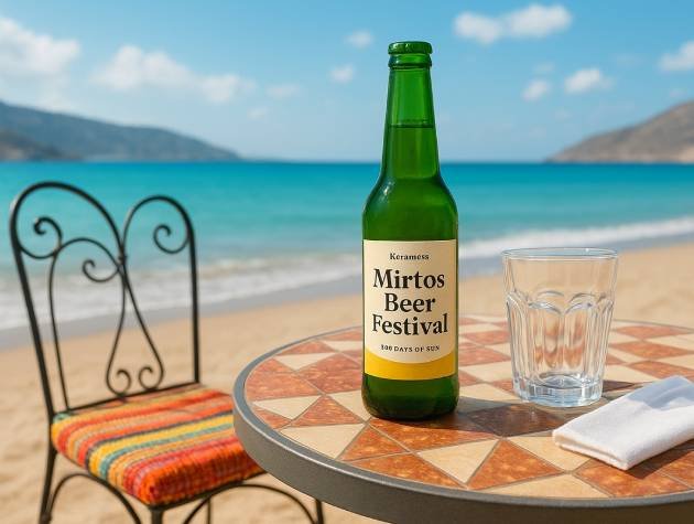 Bottle of Mirtos Beer Festival craft beer and glass on a table by the beach in Myrtos, celebrating local festivities and Cretan culture.