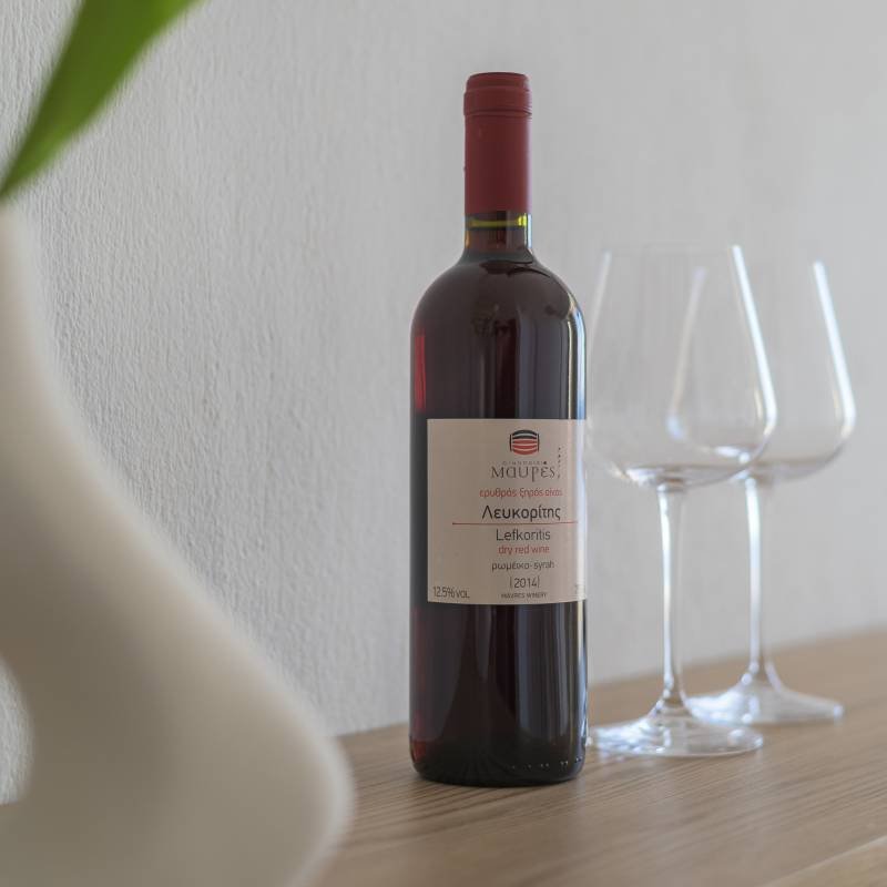 Complimentary Cretan Wine Welcome - Panorama Myrtos Close-up of a welcome bottle of Cretan red wine and two glasses, symbolizing the warm hospitality and welcome gift for guests at Panorama Myrtos.